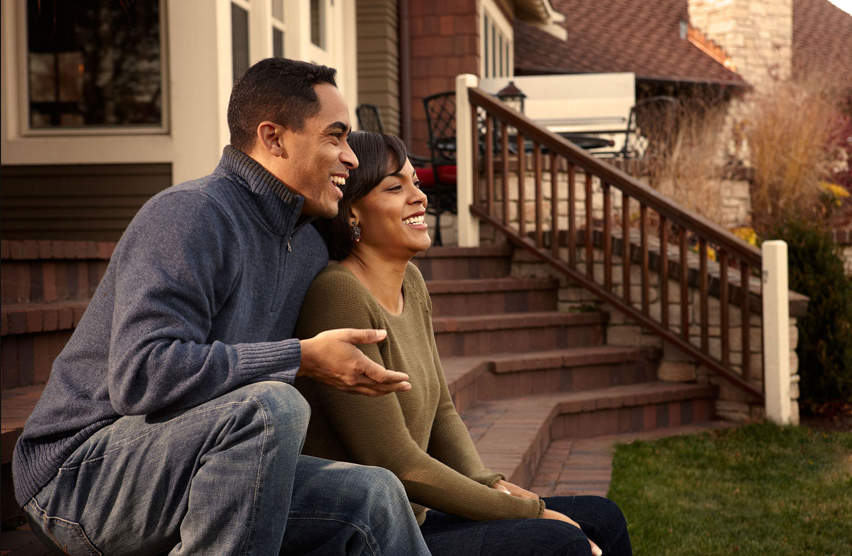Young African American couple sitting on the back yard deck.